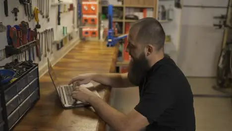 Caucasian master using laptop in bicycle workshop