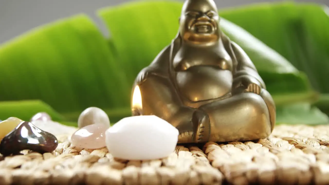 Close-up of laughing Buddha figurine with pebble stone