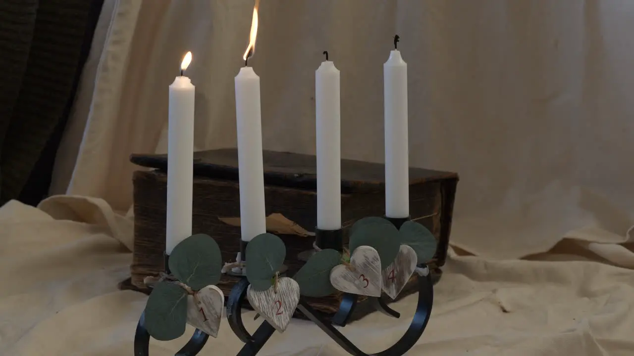 A hand lights four candles in holder for ceremonial setting