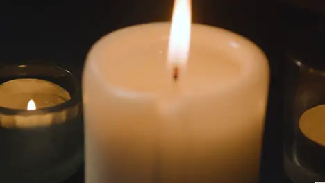 Close Up Of Candles Burning On Table In Dark Room