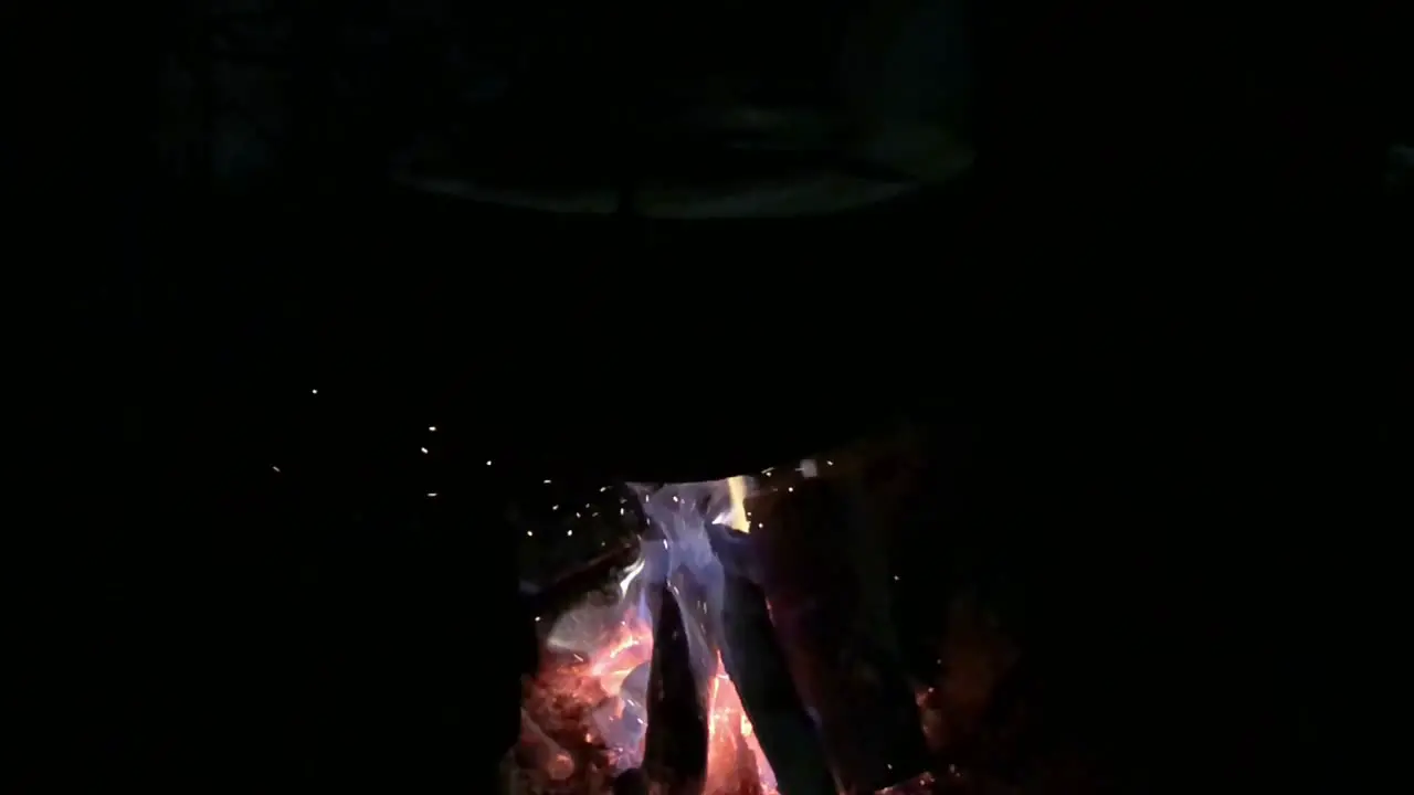 Glowing blue and red fire blazed and flames under cooking pot in complete darkness