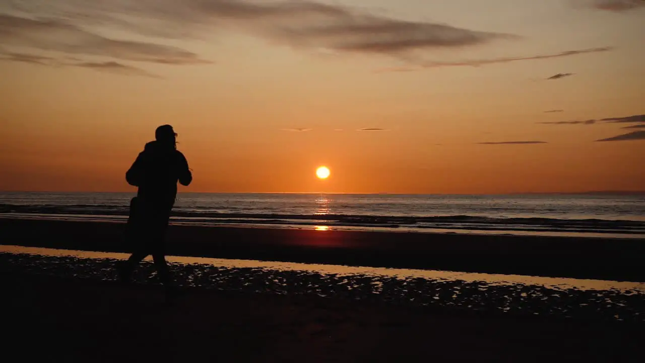 Man running with guitar in back sand beach at sunset-3