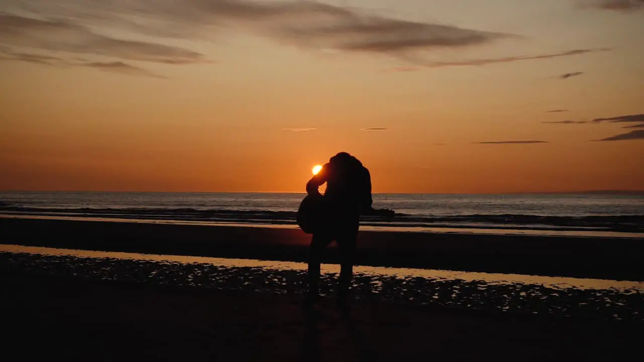 Man running with guitar in back sand beach at sunset-4