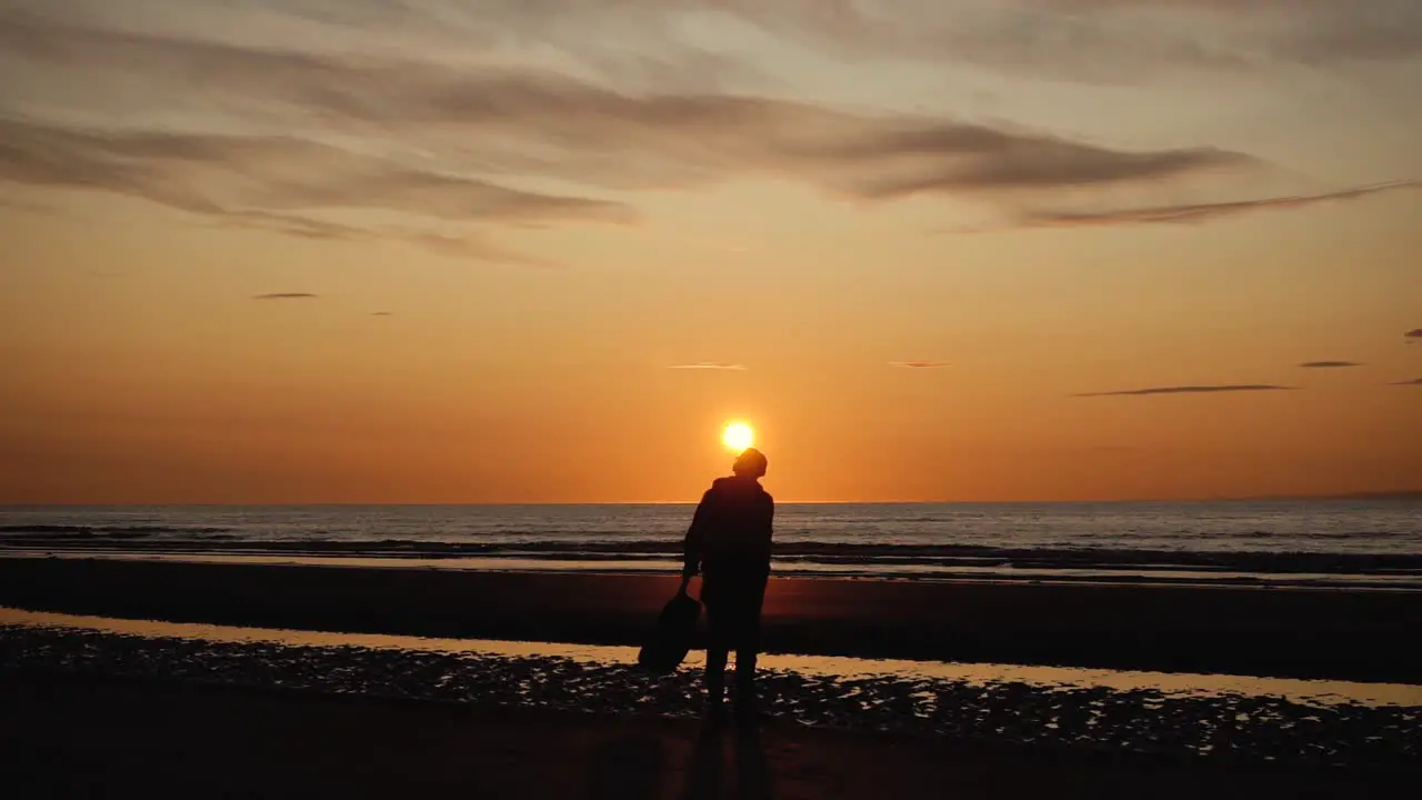 Man running with guitar in back sand beach at sunset-19