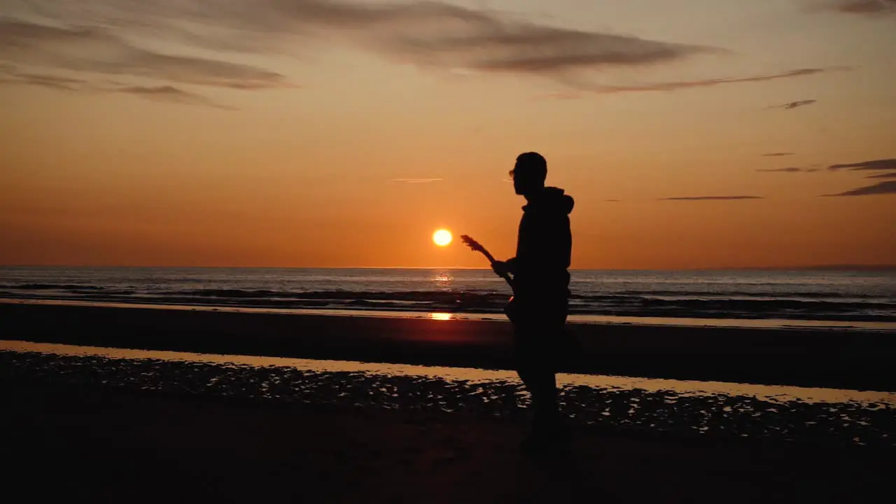 Man running with guitar in back sand beach at sunset-12