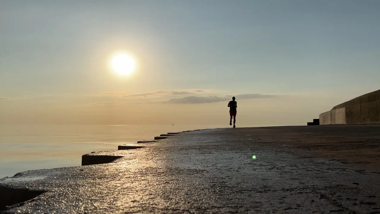 Silhouette of a runner going away from the camera along the Chicago lakefront at sunrise