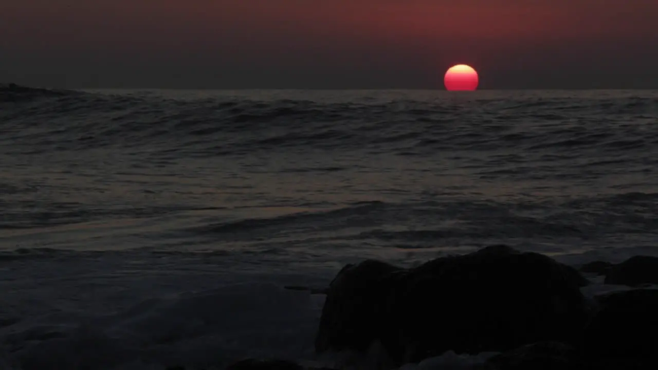 Time lapse shot of sun setting behind ocean waves