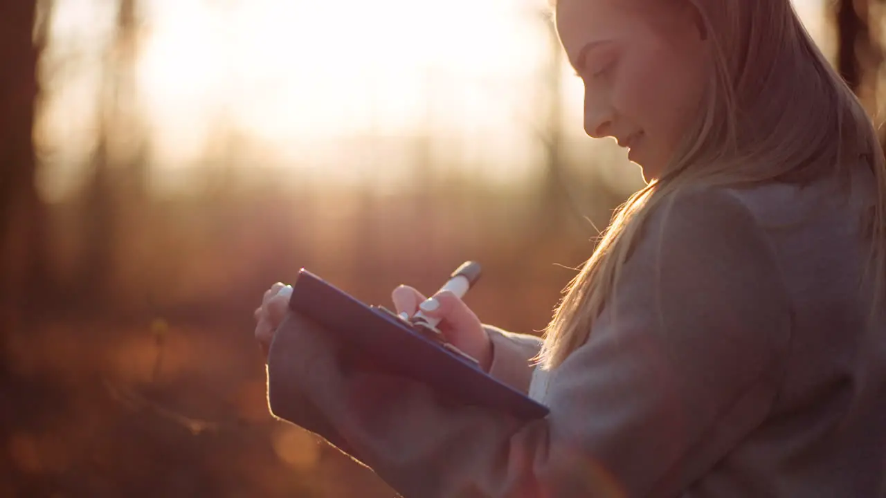 Woman Drawing On Paper Aganist Sunset