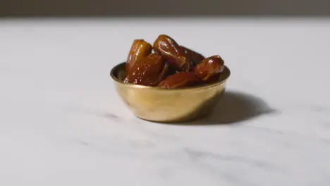 Close Up Of Bowl Of Dates On Marble Surface Celebrating Muslim Festival Of Eid