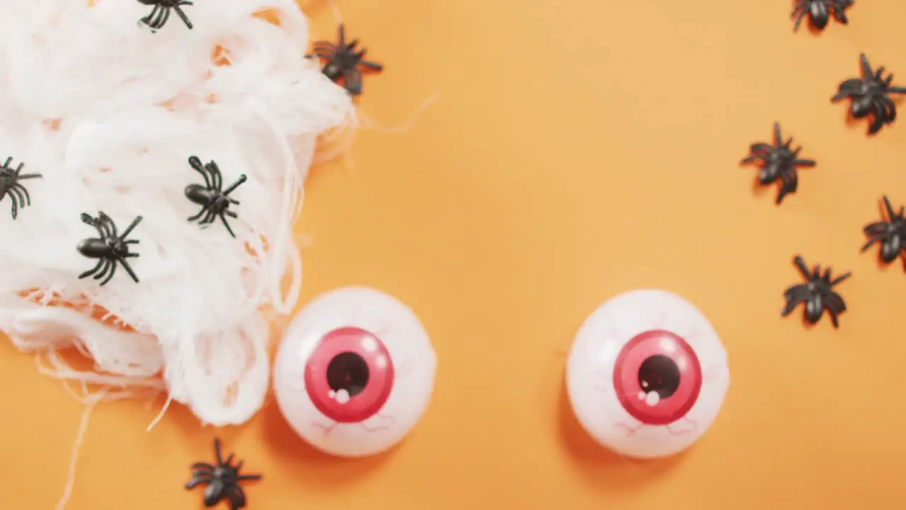 Close up view of scary eyes and spider toys against orange background