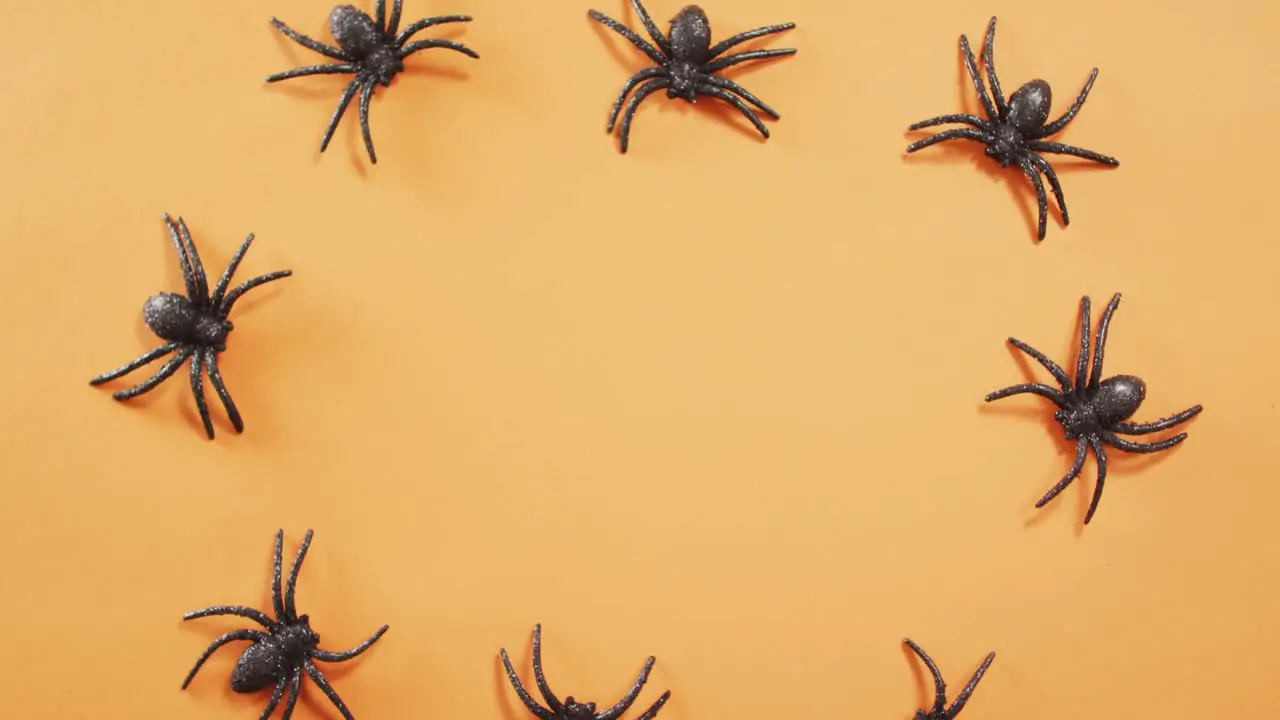 Close up of multiple spider toys with copy space against orange background