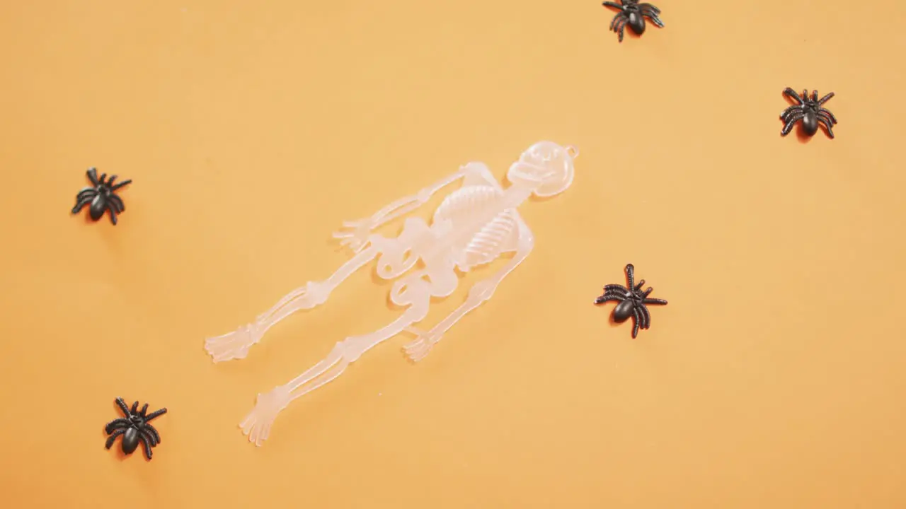 Multiple skeleton and spider toys with copy space against orange background