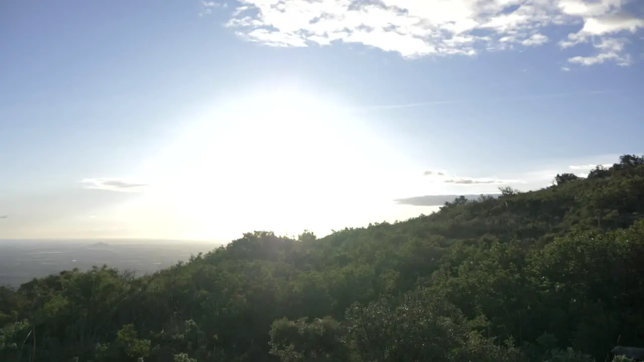 Panning on top of a mountain looking at blue skies and lots of trees in a forest in Spain