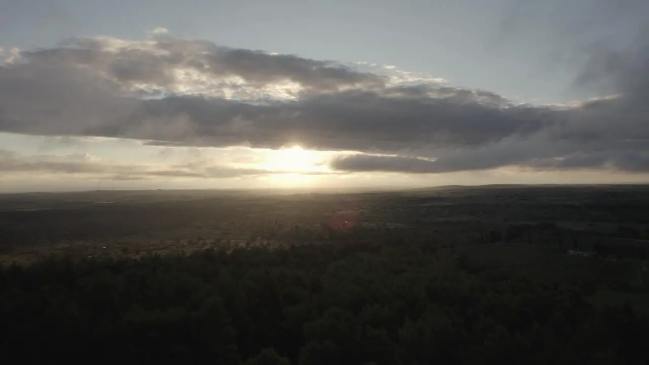 Drone flying over a beautiful Italian landscape with farmfields and nature with the sun breaking through the clouds at sunrise in 4k