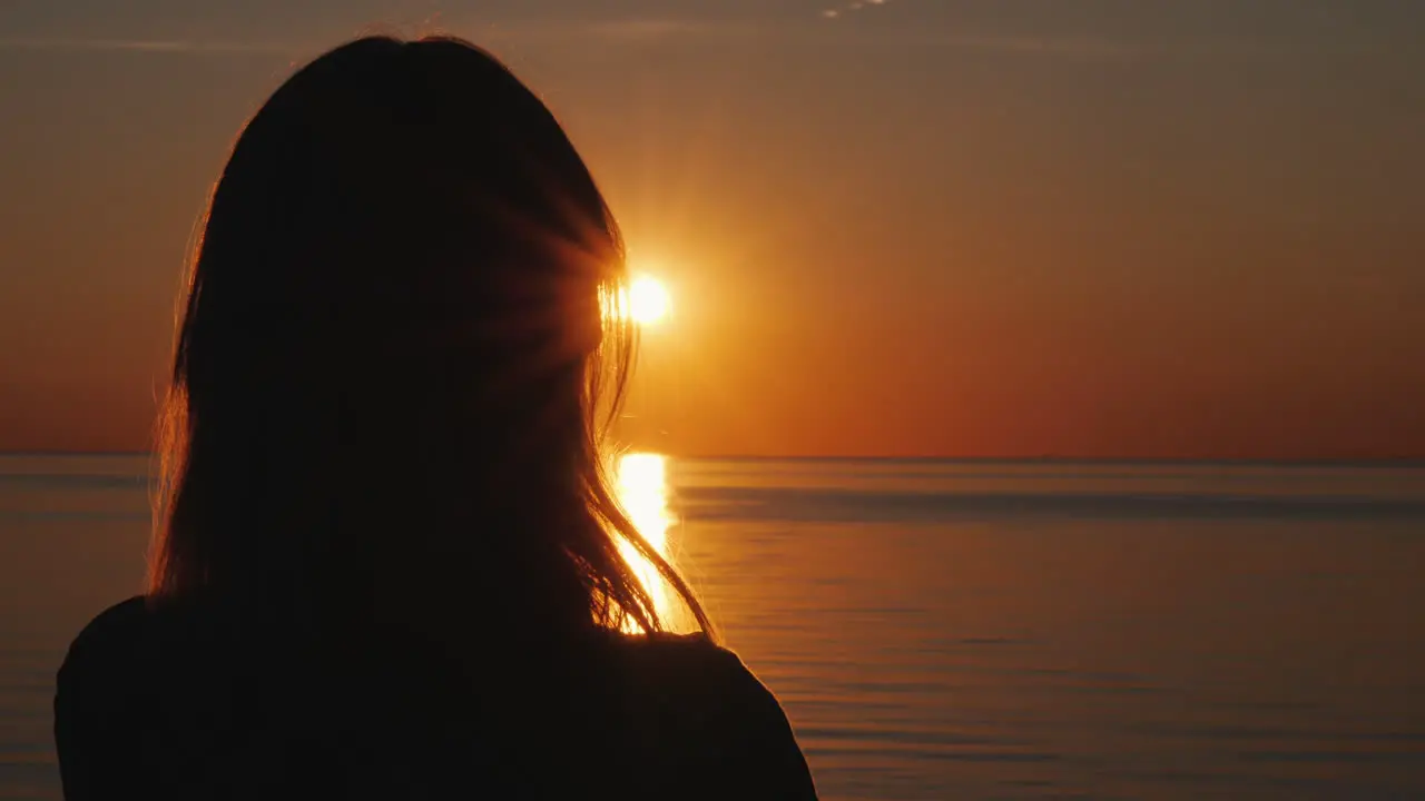 Silhouette Of A Middle-Aged Woman Who Watches The Sunset Over The Sea