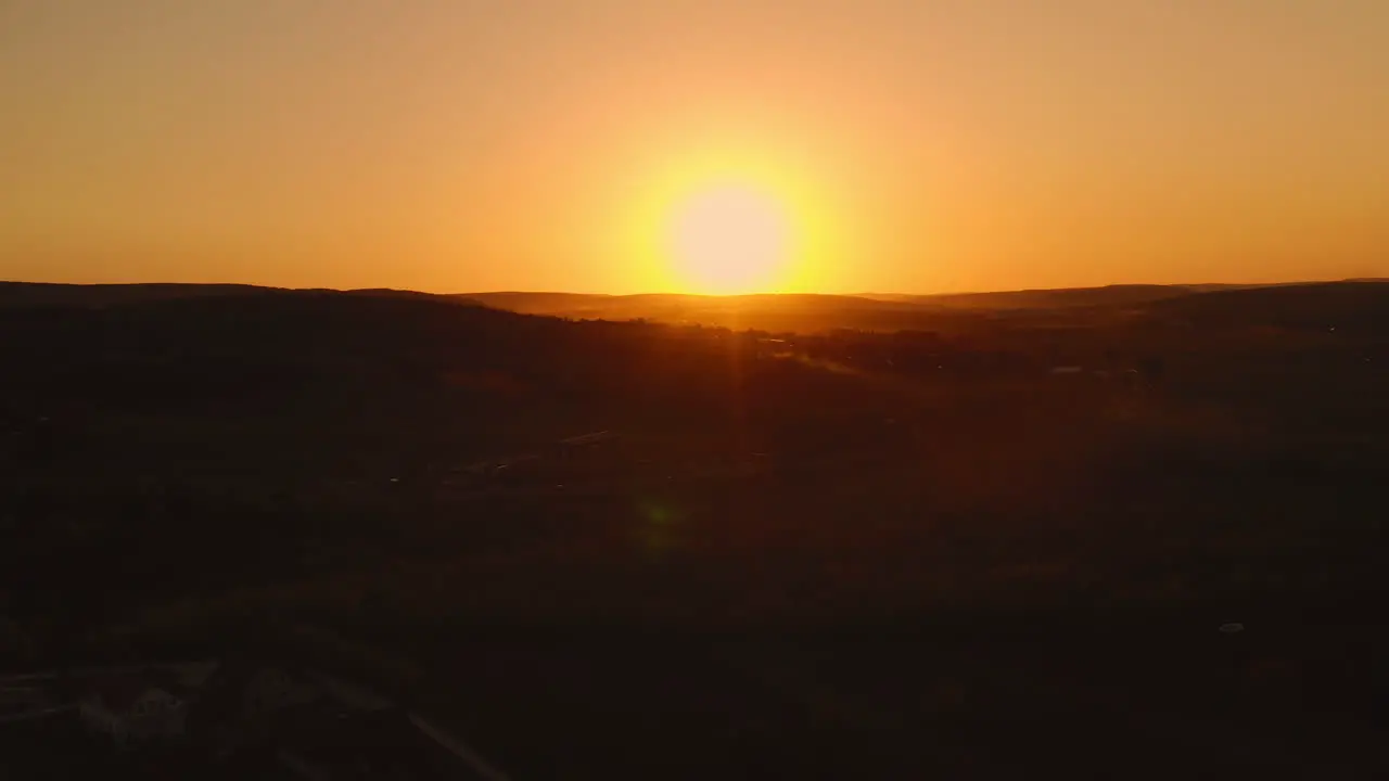 Landscape aerial drone shot of an amazing yellow sunrise above morning fog and clouds over a village in Moldova