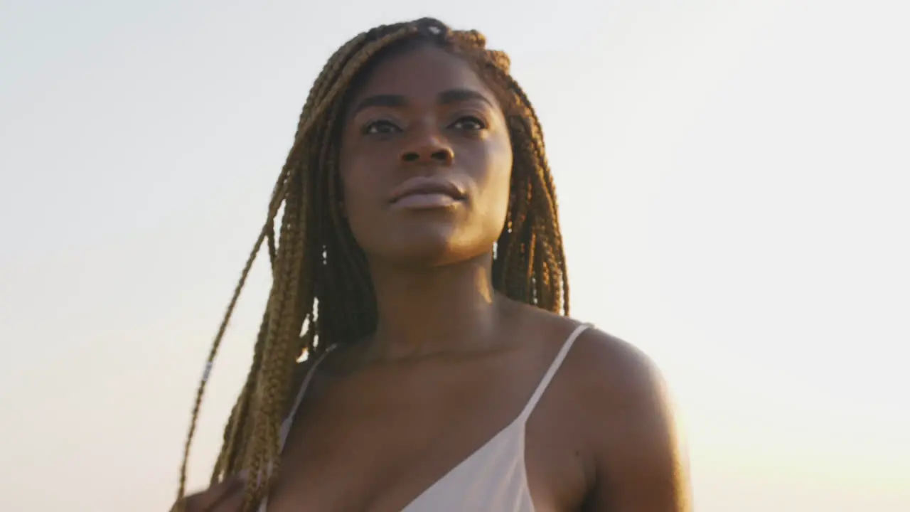 African bikini model with braids posing at the beach during a sunset