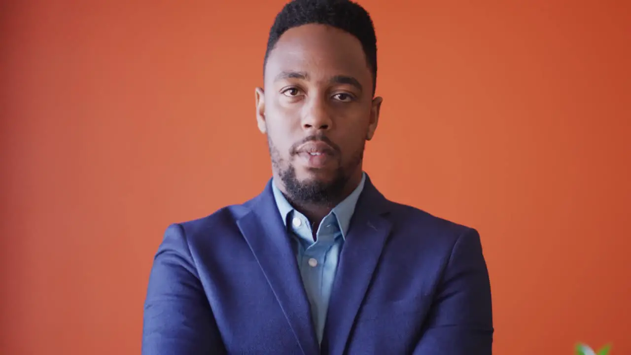 Video of smiling african american man looking at camera on orange background