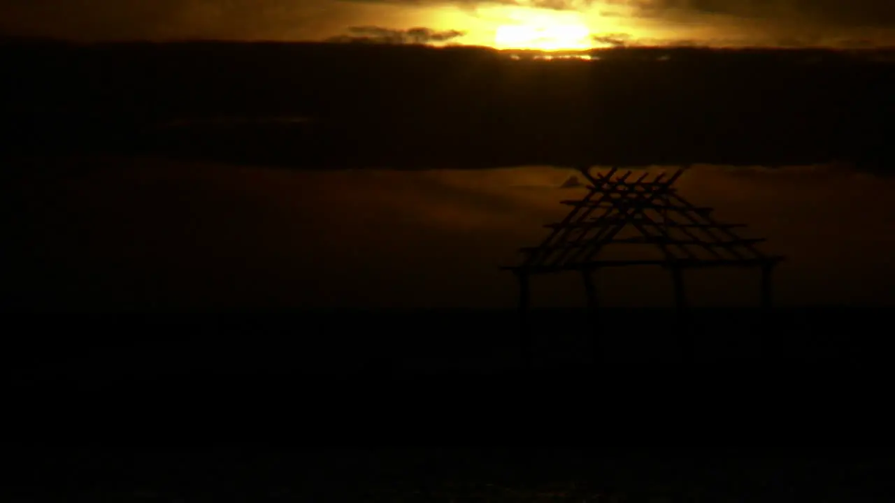 The sun sets on a cloudy day over a hut in Hawaii