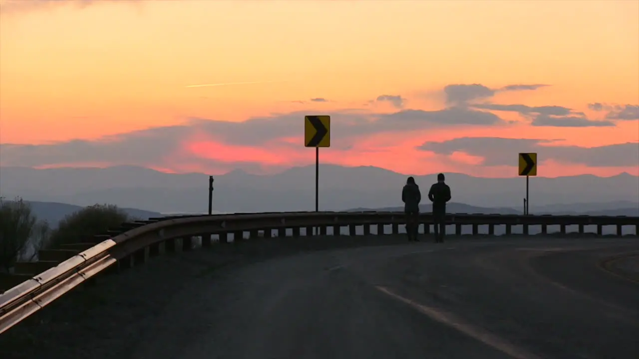 A Couple on the side of a Highway watching the Sunset