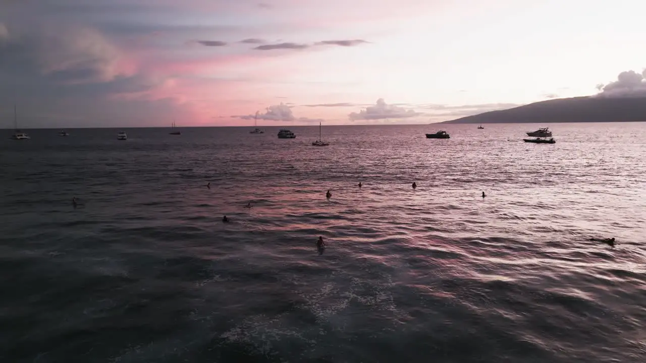 Surfers enjoying a pink sunset sky in West Maui Hawaii