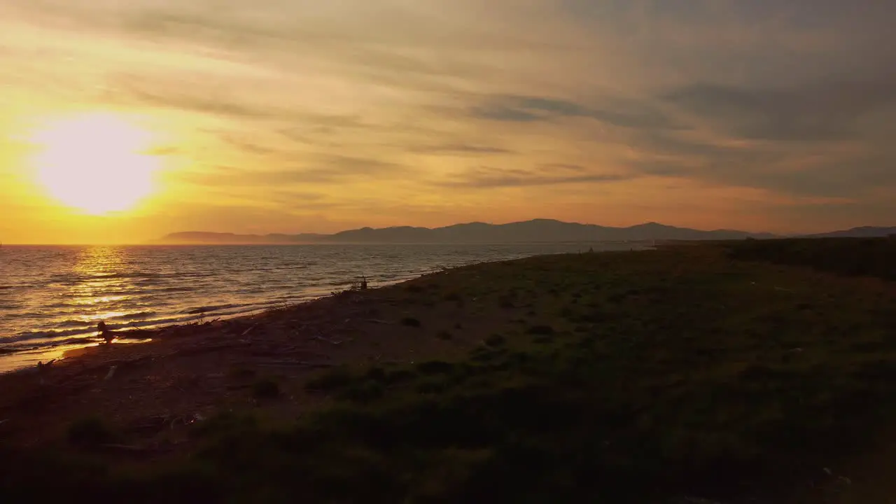 Cinematic aerial drone footage of the sunset at a sandy beach at the seaside near Alberese in the iconic Maremma nature park in Tuscany Italy with waves islands and a dramatic red sky