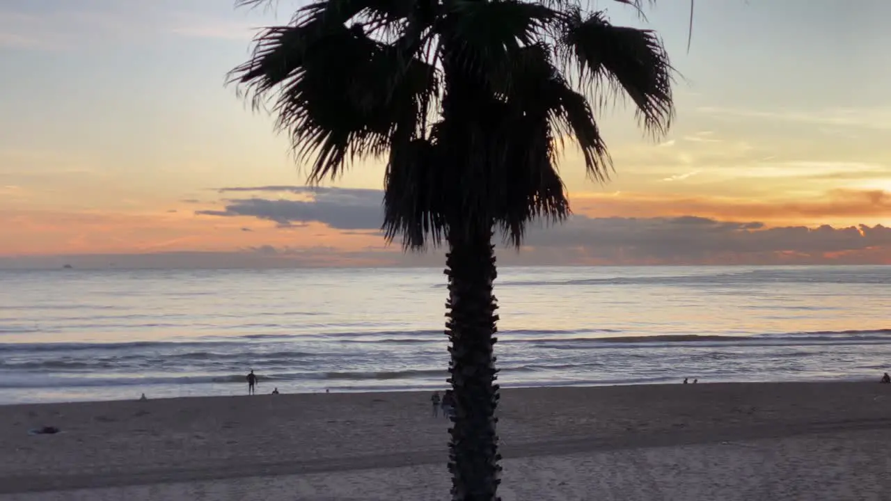 Tourist carrying surfboard running to the sea surfing with amazing sunset in middle of clouds