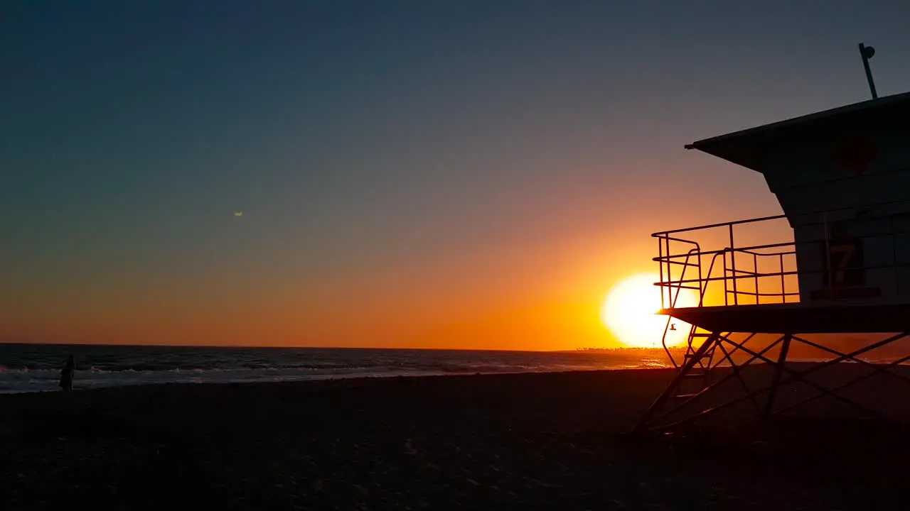 Slow sunset shot moving towards and passing Lifeguard house  tower at San Buenaventura State Beach in Ventura California United States