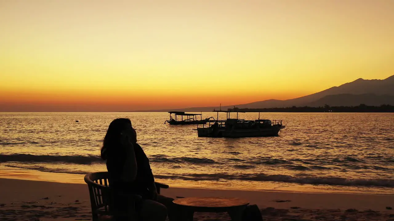 female freelancer answering the phone on the private sandy beach dream land during the sunset