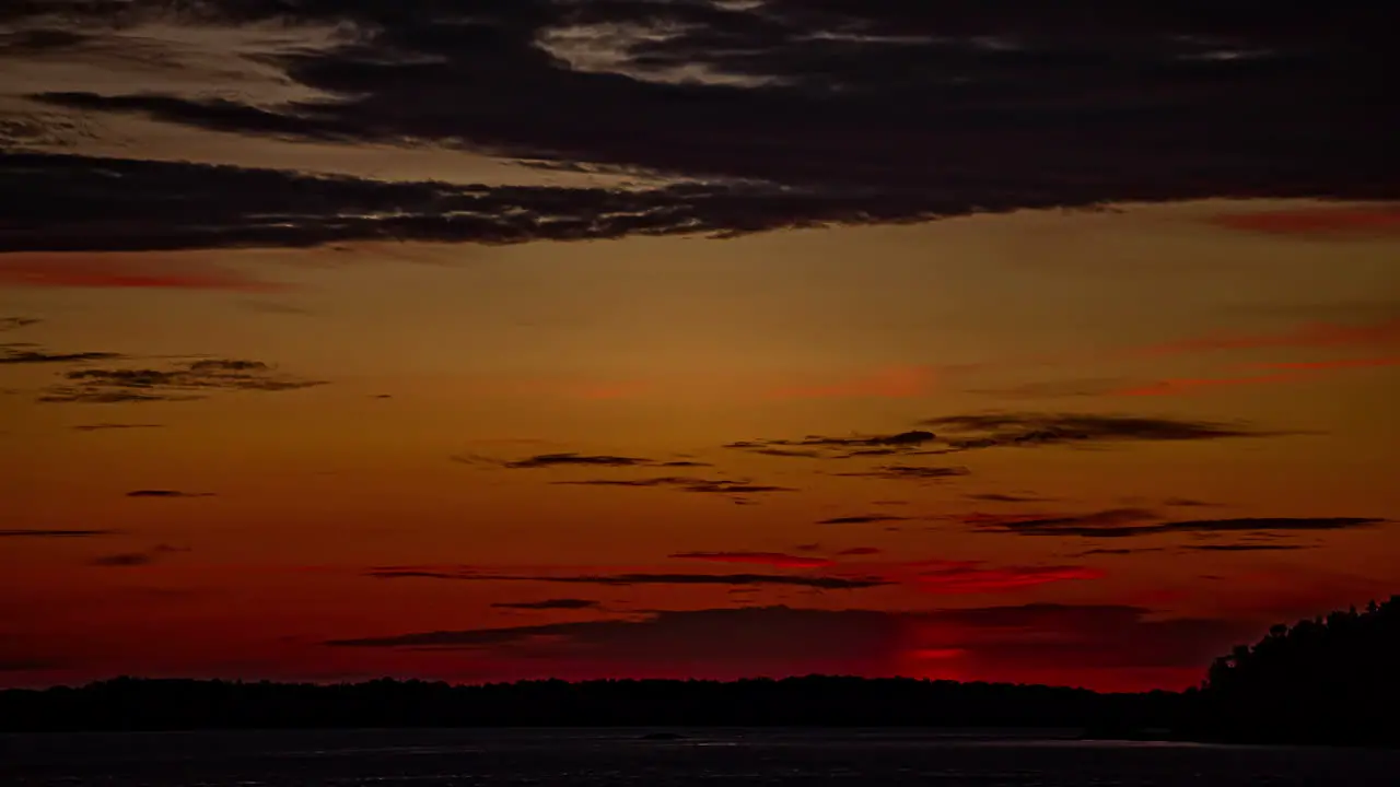 Colorful sunset to twilight time lapse above the silhouette of the forest and countryside