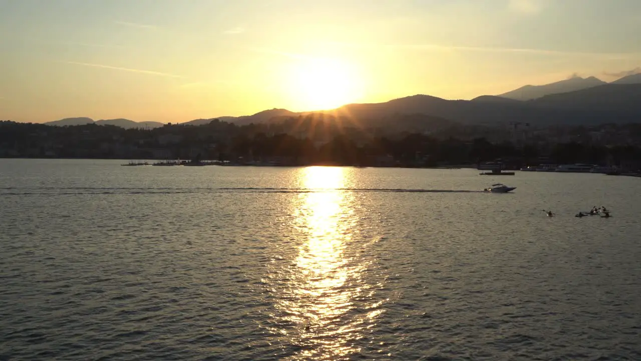 Speedboat crosses lake with beautiful sunset behind mountains surround the landscape