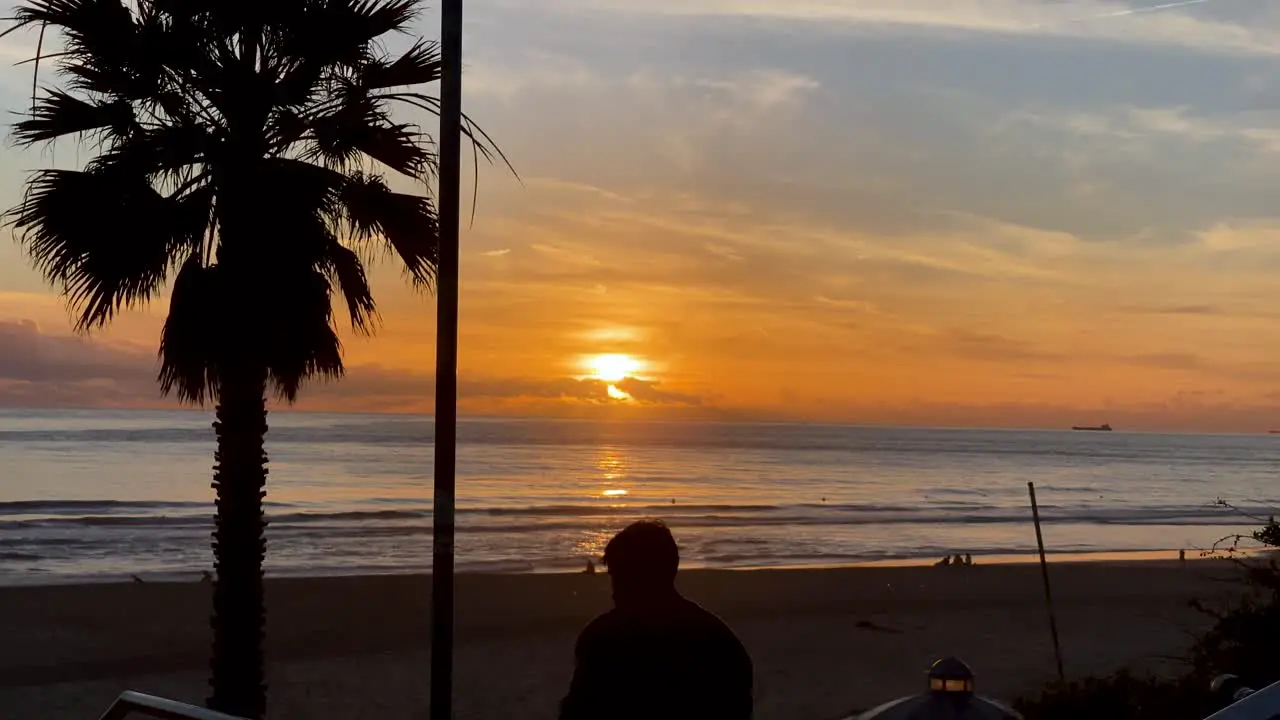 silhouette of man at Carcavelos beach Slowly waves form and break beautiful Atlantic ocean deep yellow sunset on water reflections Portugal