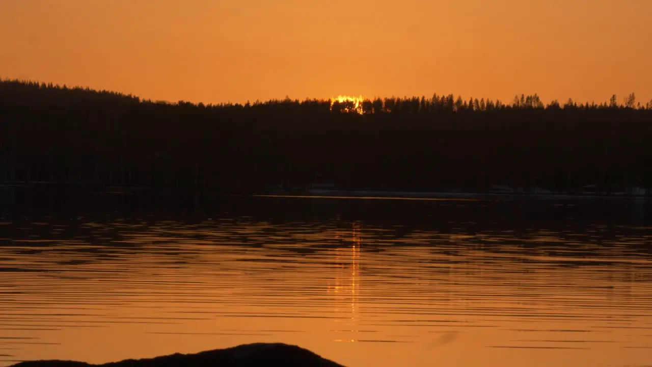 River bank Time-lapse of golden sun setting behind dark alpine hills