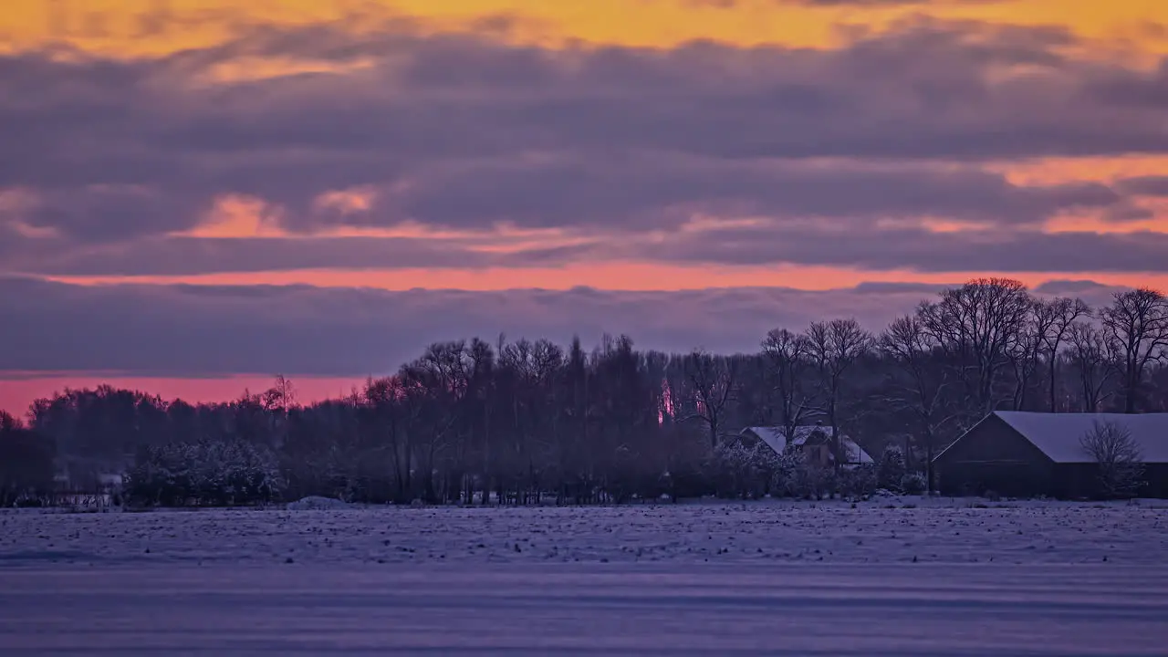 Sunset Time lapse of snowy field with houses and forest