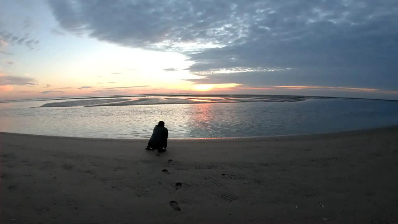 Drone aerial footage of a man taking photographs of the sunset by the ocean