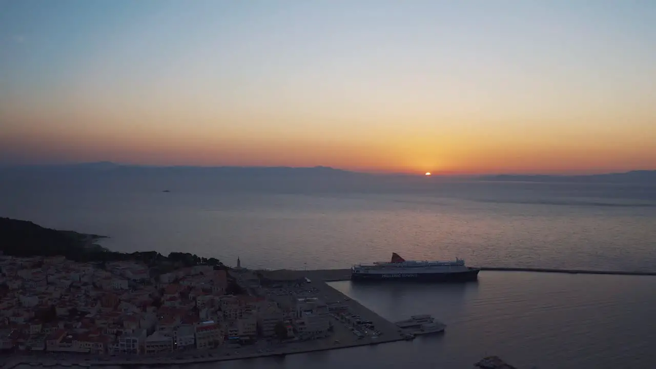 Aerial drone Flight over downtown mitilini revealing sunrise at sea with ferry to athens lesvos greece