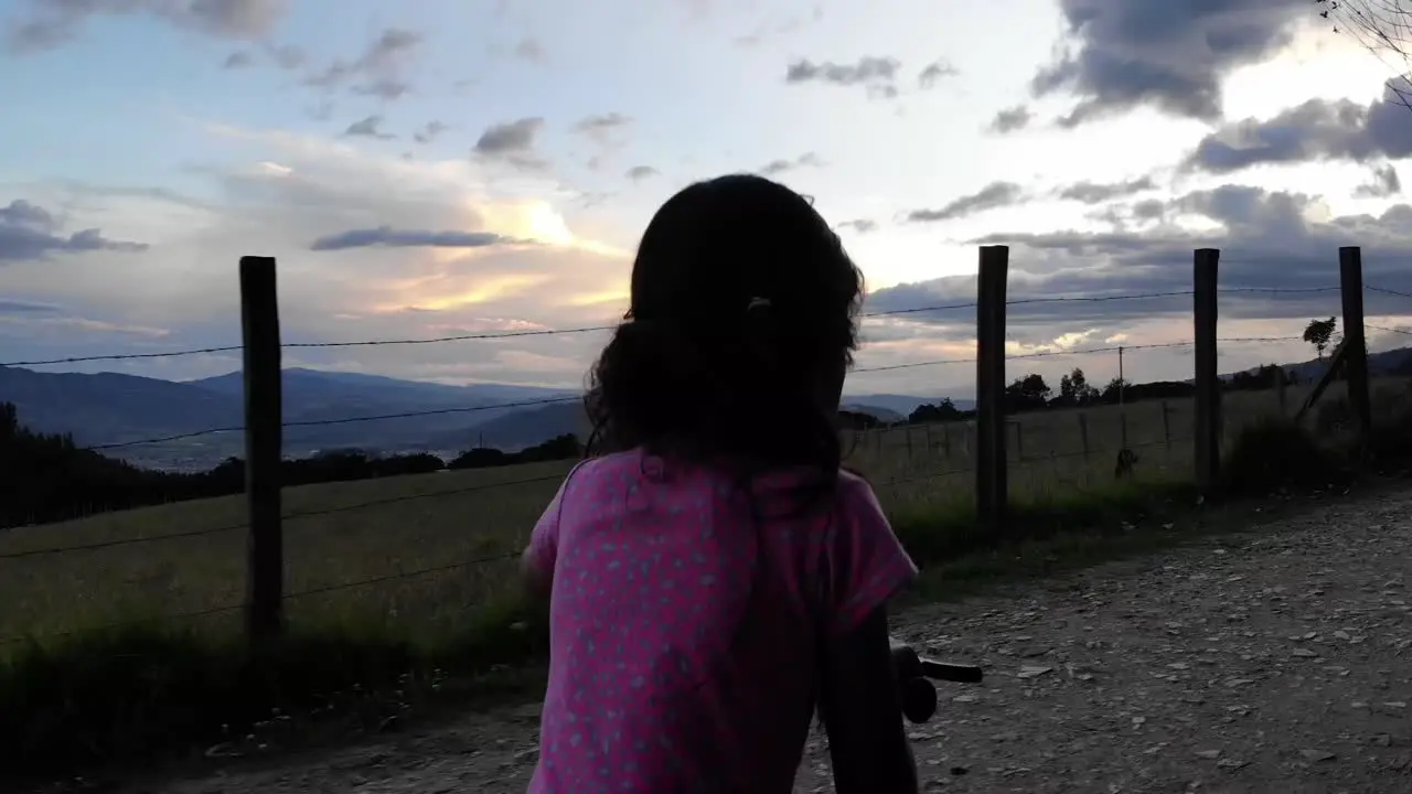 Close-up shot of a young girl pushing her bike along a rural dirt road