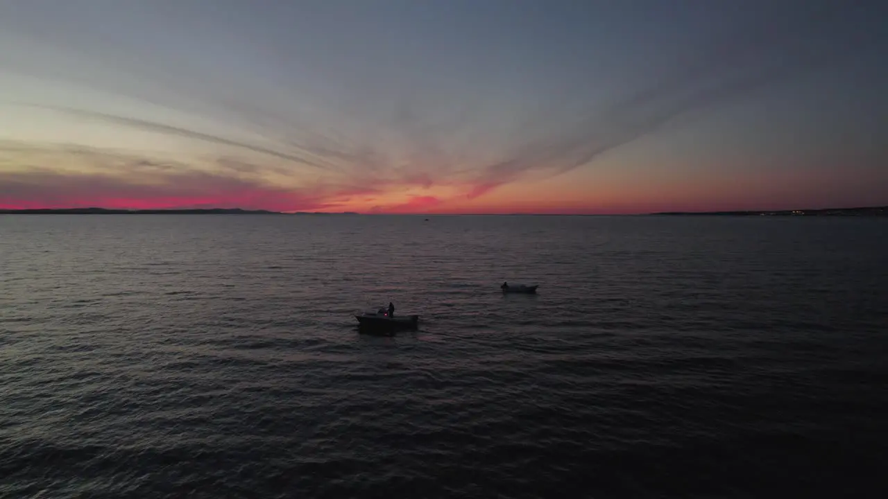 Twilight scenery of two local fishing boats floating on calm sea nightfall aerial