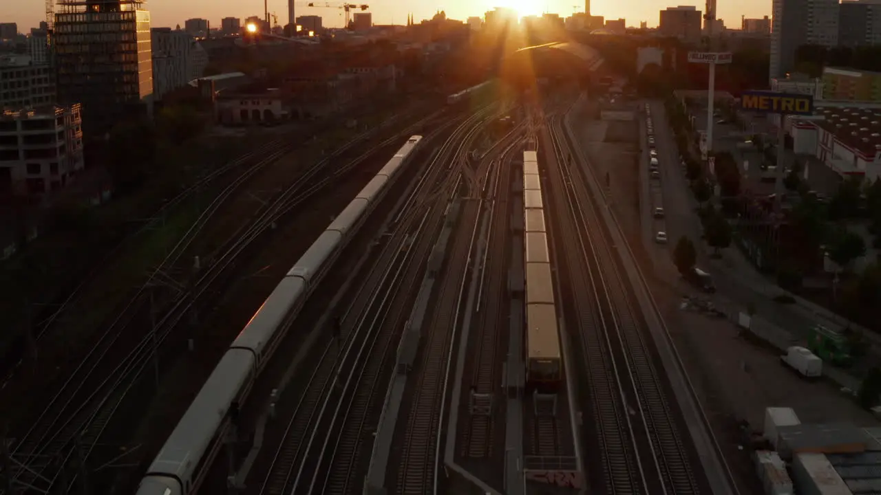 Beautiful Establishing Shot of white passenger Train on driving into Sunset over Berlin Germany Golden Hour Cityscape and Ostbahnhof Central Train Station Aerial Wide Angle