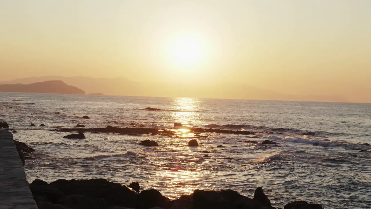 Slow motion shot of Sunset over ocean waves crashing against stones beautiful aegean sea background in chania Crete Greece