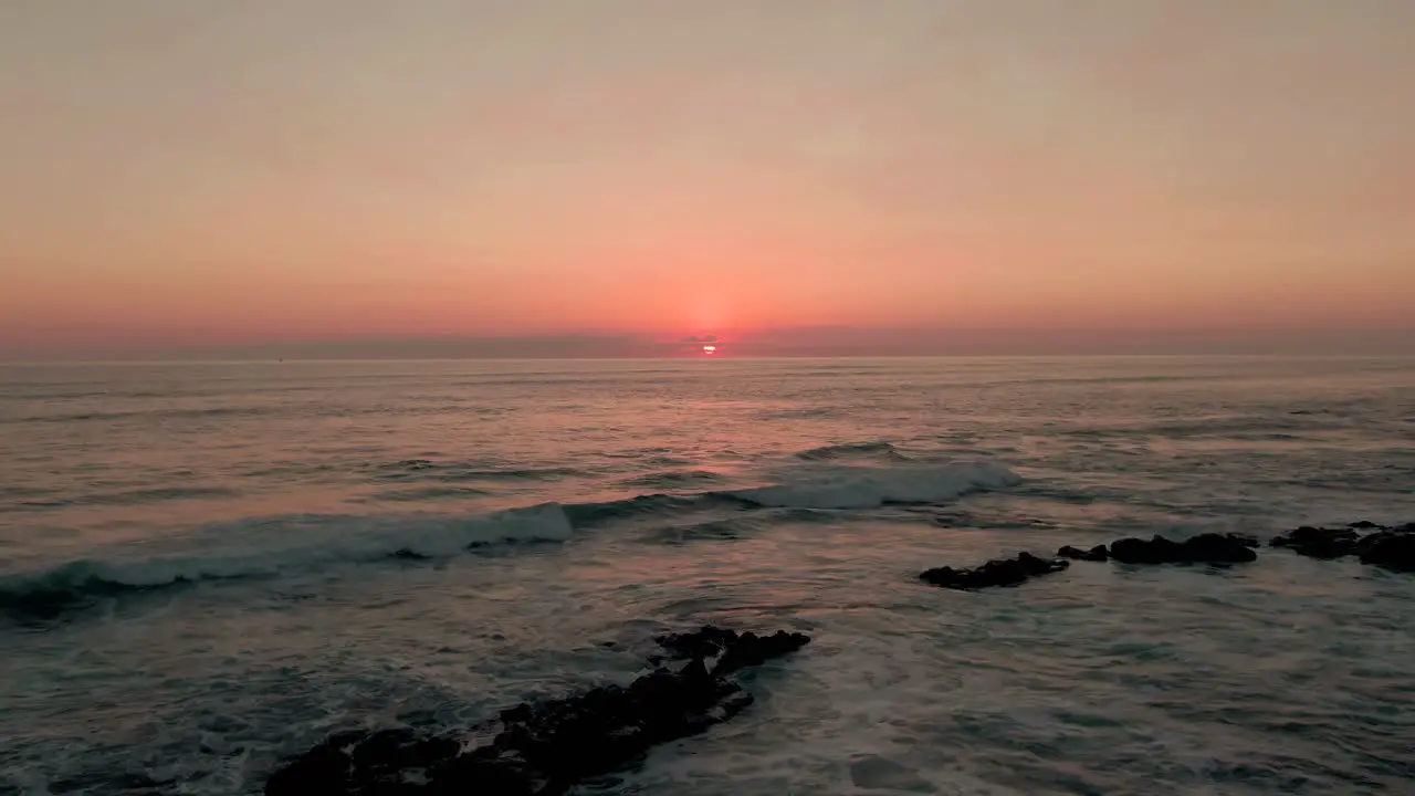 Aerial view with backward motion of pink sunset reflected in Caribbean ocean