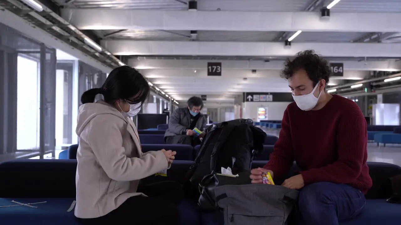 Couple wearing facemasks sitting at airport during corona crisis