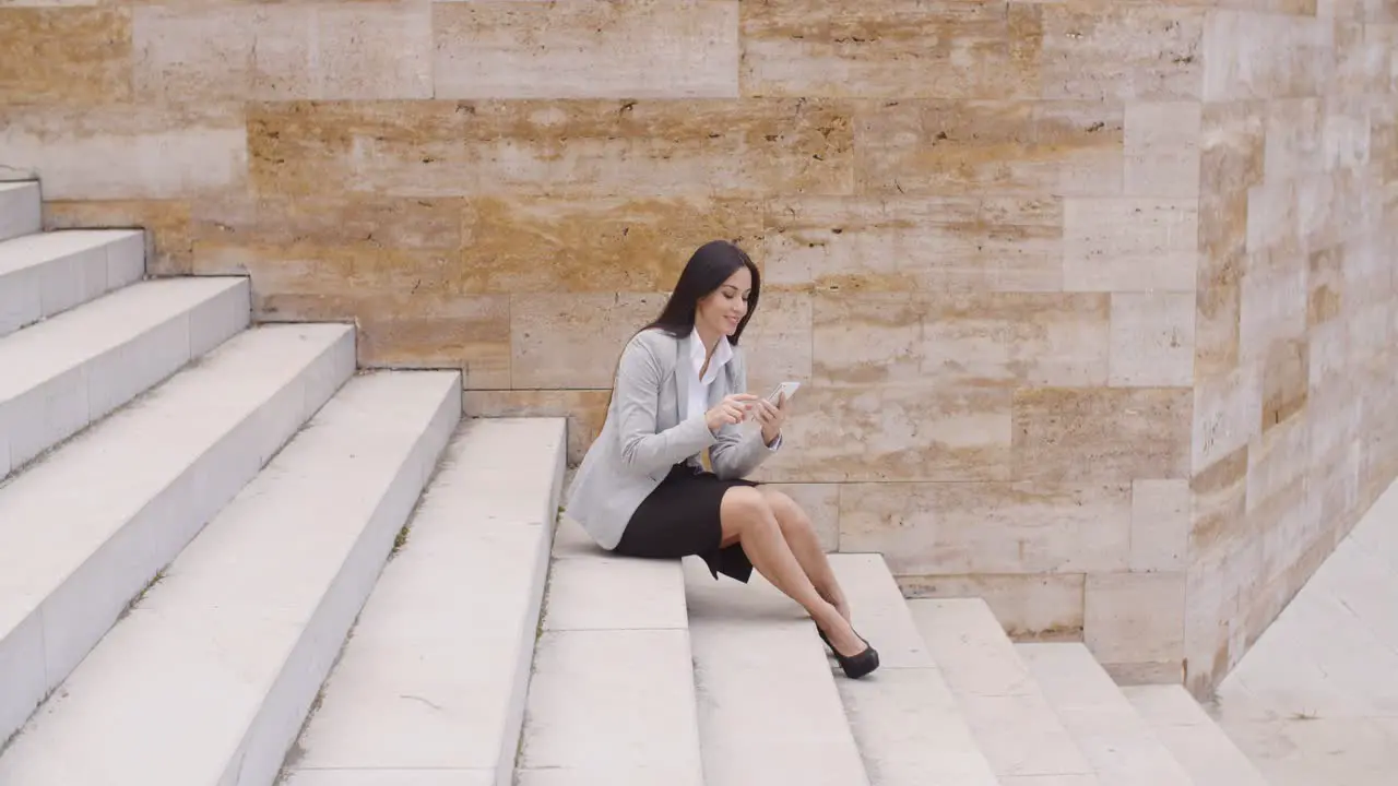 Pretty business woman sitting on steps using phone