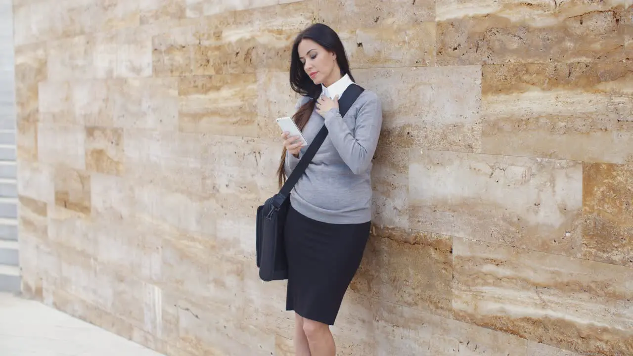 Serious woman checking email on phone outdoors