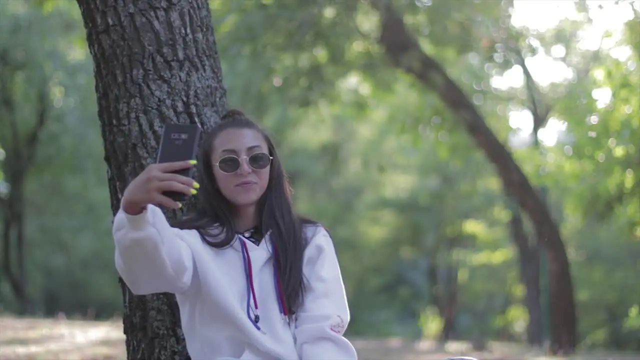 Young beautiful girl making a selfie photograph with her phone in a park