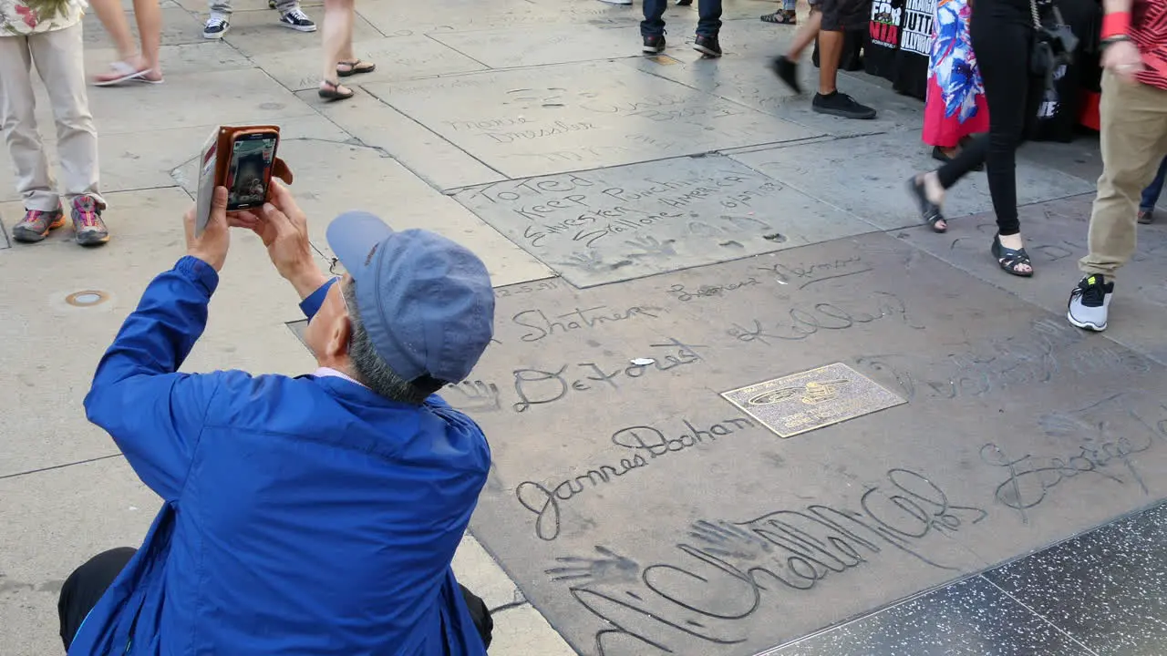 Los Angeles A Tourist Takes A Picture By Names In Concrete On The Hollywood Walk Of Fame