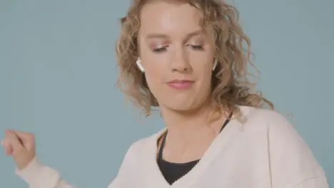 Close Up Shot Of Young Woman Listening To Music On Mobile Phone And Dancing Against Blue Background