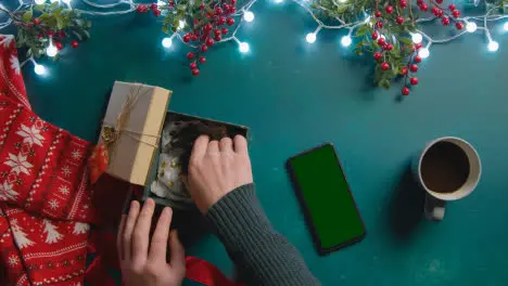 Overhead Shot Of Person With Green Screen Mobile Phone With Christmas Decorations And Gift Of Perfume