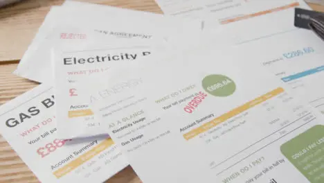 Close Up Of Man Opening Overdue UK Utility Bills And Adding To Pile On Table