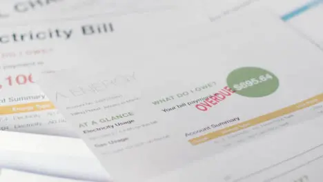 Close Up Of Person Holding Overdue US Energy Bill And Pile Utility Debts